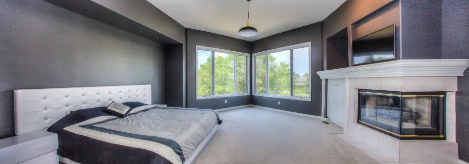 Master bedroom with bay window and grey upholstered bed