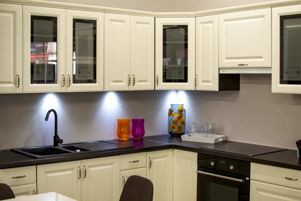 Cream modular kitchen with black countertop and under-cabinet lighting